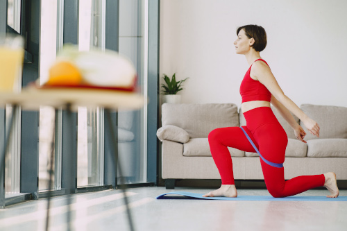 Femme en tenue de sport rouge faisant du yoga chez elle